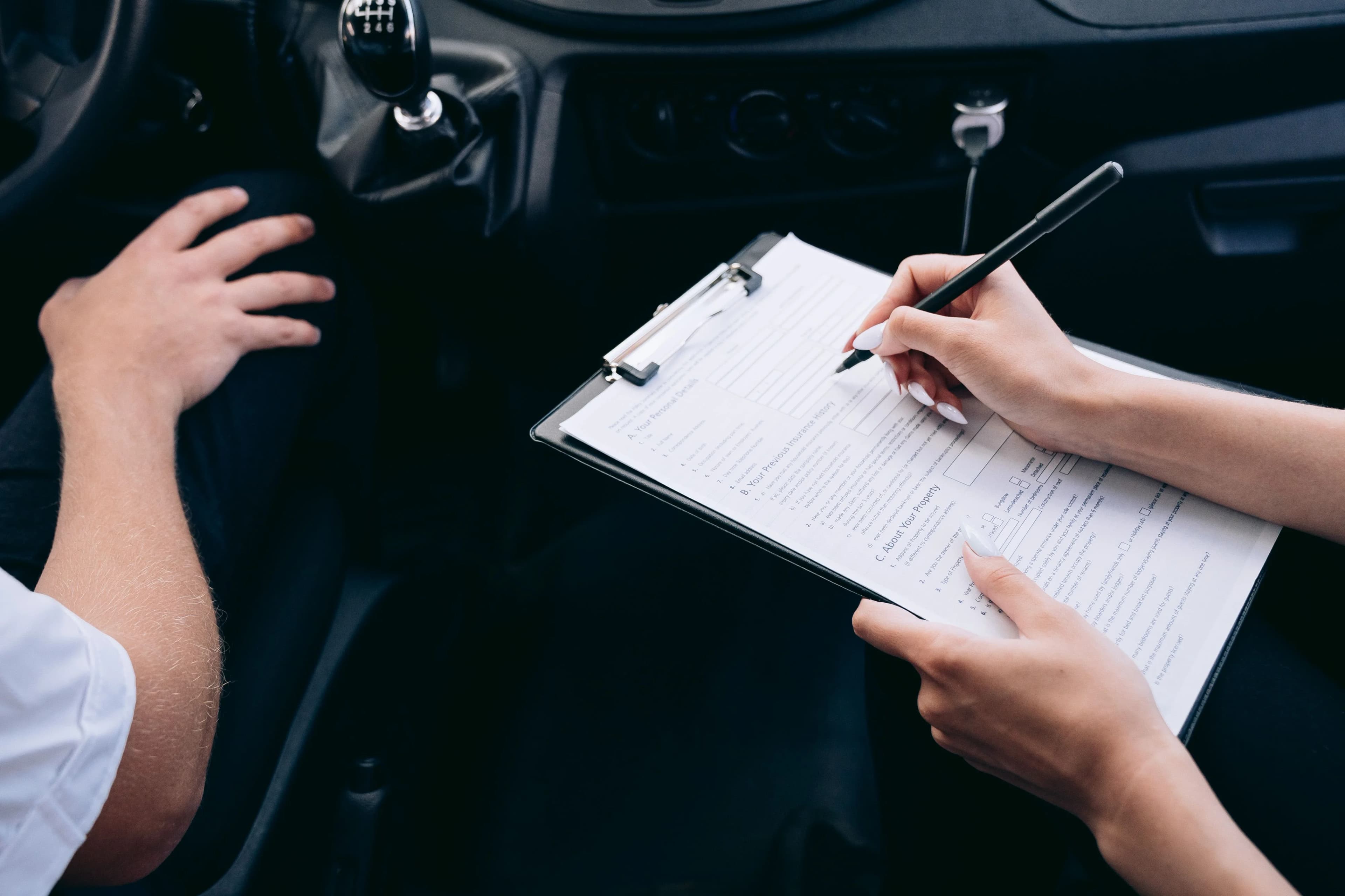 An examiner reviews a checklist with the candidate during the practical driving test
