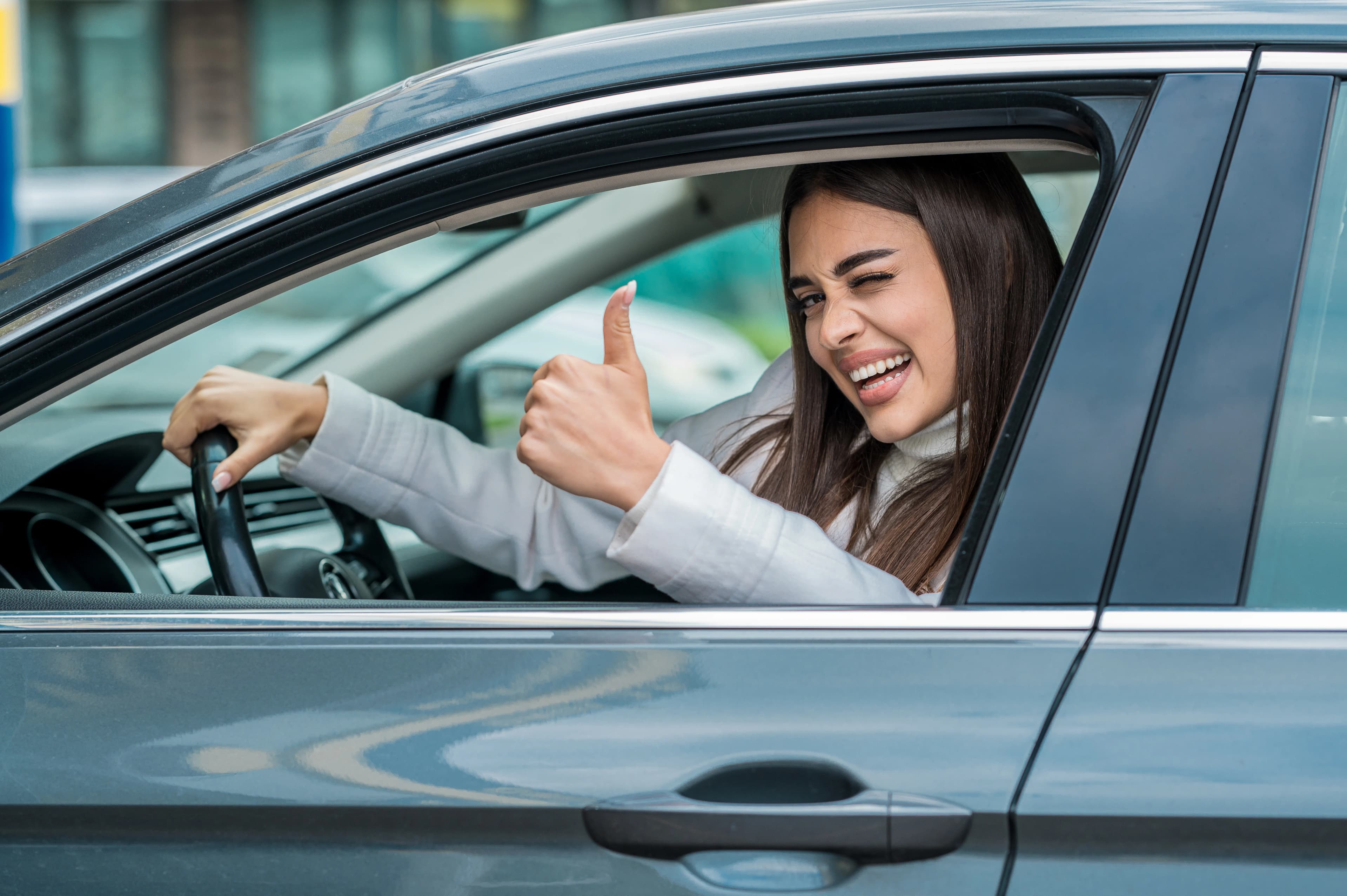 Kandidaat steekt duim omhoog vanuit de auto na het geslaagde rijexamen